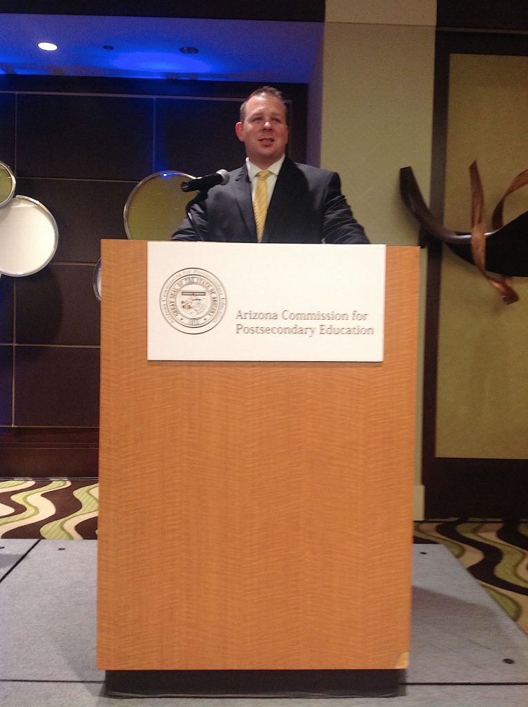 Representative Jeff Dial speaking at the Arizona Commission for Postsecondary Education podium